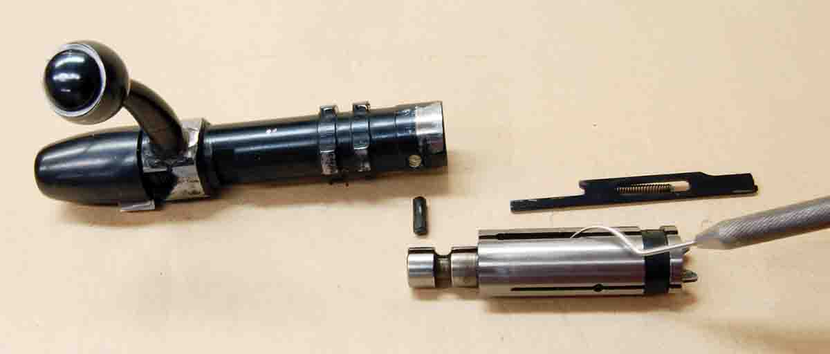 The bolt is disassembled by driving out one pin. Clean-firing the pin slot with a tool like the dental pick shown.